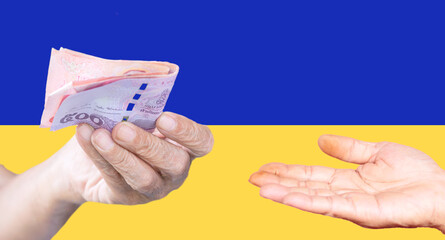 Hand holding money on Ukrainian flag, idea to help Ukrainian people