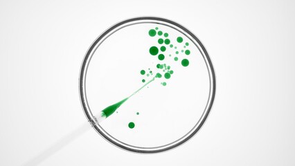 Top view macro shot of lab dropper injects green oil into clear fluid creating different sized...
