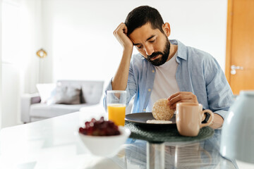 Depressed man at the table suffering from lack of appetite - obrazy, fototapety, plakaty