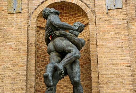 The sculpture of wrestling Hercules and Antaeus next to the wall of the Parma Town Hall on the top of the fountain, Italy.