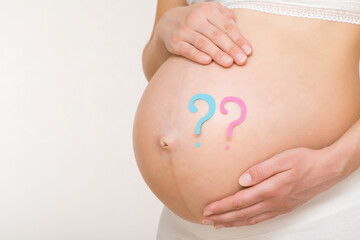 Pink and blue question marks on young adult pregnant woman big naked belly. Guessing future baby...