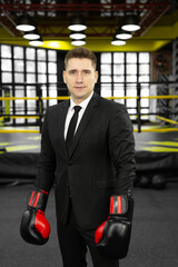 Portrait of a young male businessman in boxing gloves in the ring.