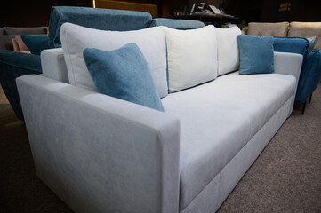 Exhibition of soft furnishing in the furniture store showroom. Stylish minimalist sofa with velour cushions in the showroom of a furniture store