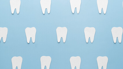 Top view of white teeth shape made from paper on light blue backgrond. Dental concept. Minimal.