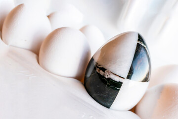 Fototapeta premium Eggs of different colors in cardboard boxes. marble stone egg on a background of white chicken eggs