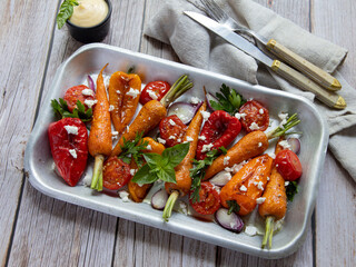 baked grill carrots, tomato, bell pepper in a plate, basil and spices vegan dish, close up, goat cheese