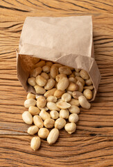 Peeled peanuts in a paper bag over wooden table