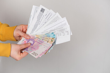 Hryvnia banknotes and payments for utilities are in the hands of a person. Payment for gas, electricity and water in Ukraine.