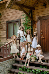 Tween girls posing on threshold of wooden rural house on summer day
