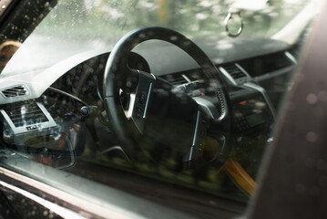 Car interior, dashboard view through window outside. Selective focus on steering wheel