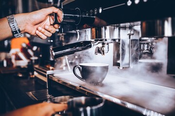Barista making coffee with coffee machine in cafe.