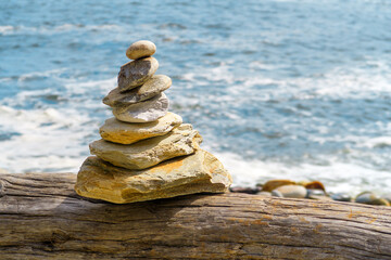 stacked rocks on a tree trunk  with seawater background