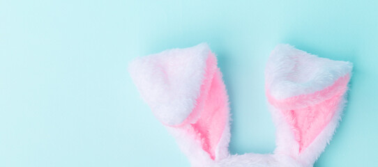 Toy bunny ears on a blue background. The concept of the Easter holiday, flat lay. Minimalism. Banner