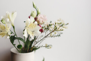 Obraz na płótnie Canvas Stylish bouquet in ceramic vase at window. Beautiful fresh flowers, Manuka, alstroemeria, eustoma, eucalyptus floral arrangement. Spring modern bouquet close up
