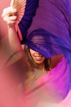 Woman waving bright fabric while dancing in studio