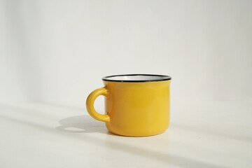 Yellow small coffee cup mockup for design presentation, white background with sunlight.