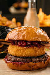 burger with beef cutlet, camembert and cherry on a wooden table in a cafe. close up