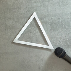 Simply. Microphone and silver triangle frame on gray concrete background. Text space. Top view. Minimal style.