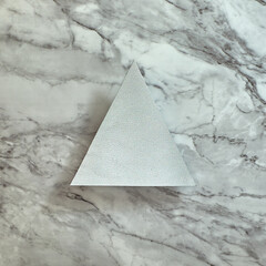 Silver triangle on a gray marble background. Text space. Top view. Minimal style.
