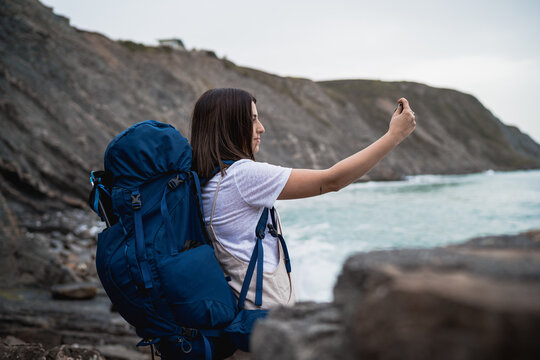 Female hiker taking photo of sea - Powered by Adobe