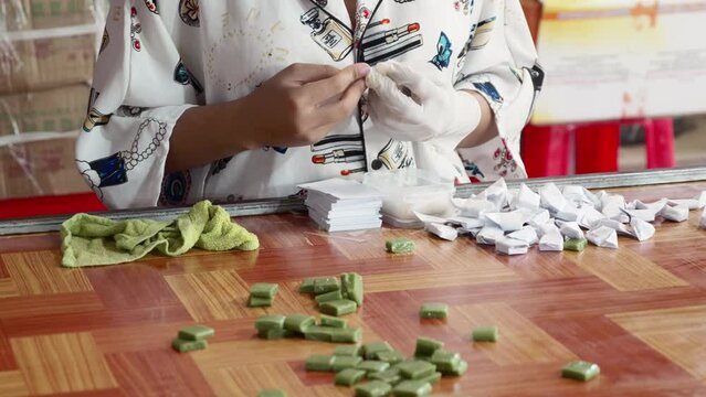 Close up of woman hands packing coconut candy at home, Vietnamese sweets
