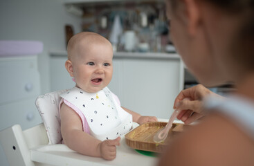 baby's first feeding, mom feeds a baby with a spoon