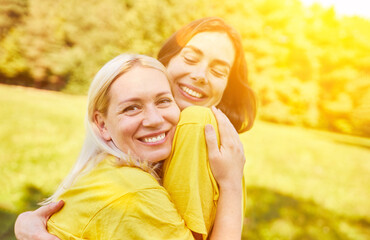 Two happy young women hug each other in summer