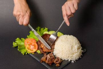 grilled beef with rice on plate over black background studio