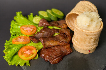 grilled beef with sticky rice on plate over black background studio