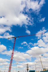 Tall red crane works under blue sky background