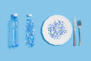 White plate full of microplastics on blue background with copy space. Plastic pollution concept,...