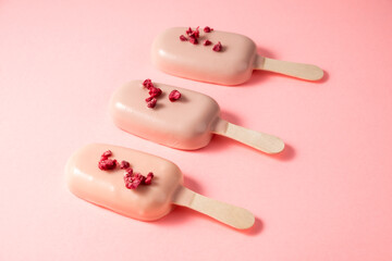 Dessert in the form of ice cream on a stick. Cakes on a stick on a pink background.