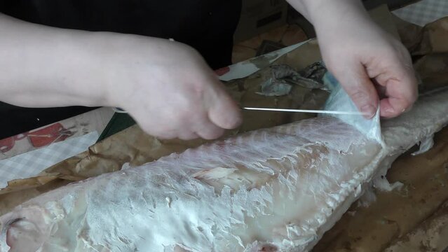 chef cleans cod fish with a knife 