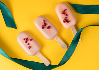 Popsicle cakes on a stick on a yellow background, top view. Ice cream in bright glaze.