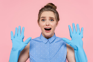shocked woman showing hands in blue rubber gloves isolated on pink.