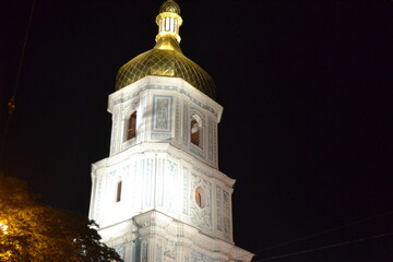 white church tower with illumination on the black dark sky in kyiv