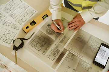 foreman or unrecognizable architect working on blueprints on construction site. Home improvement
