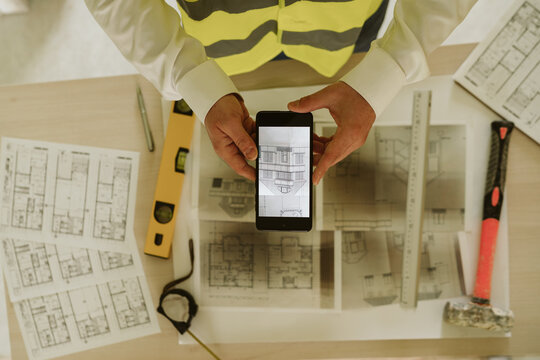 foreman or architect working on mobile phone blueprints .construction site. Home improvement