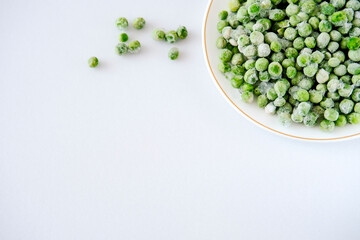 Frozen fresh peas on a light background. copyspace. Peas with ice crystals. Peas from the freezer. Peas in a light plate.