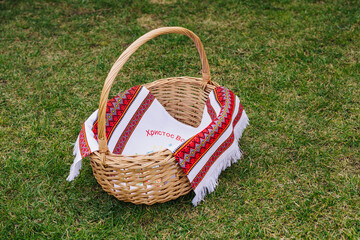 Empty easter basket on green lawn with embroidered handmade towel with text Christ Is Risen