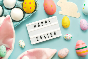Happy Easter. Light box with the text Happy Easter,colored easter painted eggs and rabbit ears.