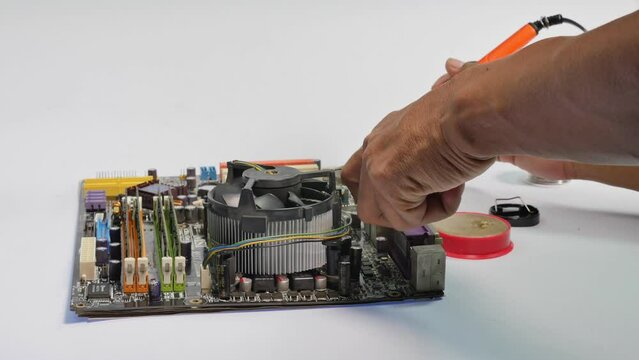 repair computer mainboard by using a soldering iron.A soldering iron is composed of a heated metal tip and an insulated handle..computer mainboard on wooden table on white background
