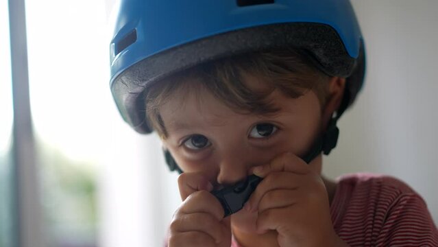 Little boy putting bicycle helmet attaching chin strap