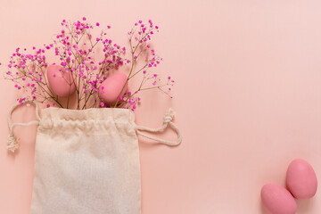 Top view of textile bag with easter eggs and pink gypsophila flowers 