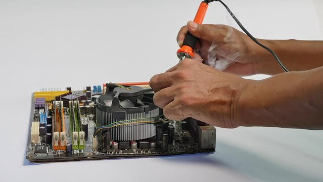 repair computer mainboard by using a soldering iron.A soldering iron is composed of a heated metal tip and an insulated handle..computer mainboard on wooden table on white background