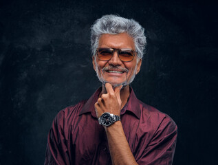Happy stylish old man with sunglasses against dark background