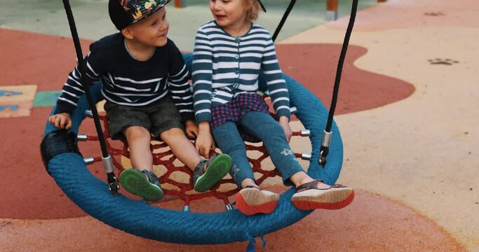 playful children having fun in basket swing at city playground