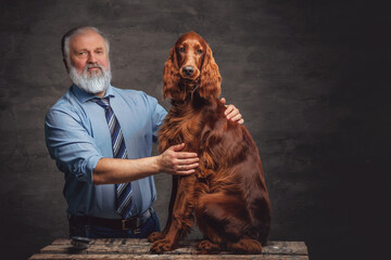 Elderly man caring about his purebred dog against dark background