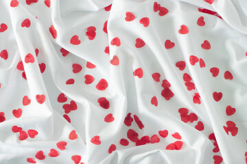 Obraz na płótnie Canvas Red hearts on a white textile background.