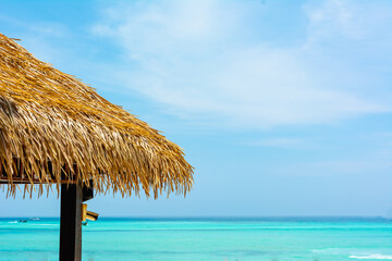 Tropical ocean hut next to the blue sea and blue sky. Copy space for  text on top right. Close-up hut grass roof at Phi Phi Island (Ko Phi Phi Don) , Krabi Thailand. Can used for travel background.